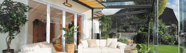 Moderner Wintergarten mit gemütlicher Sitzecke, großen Glasfronten und Gartenblick.